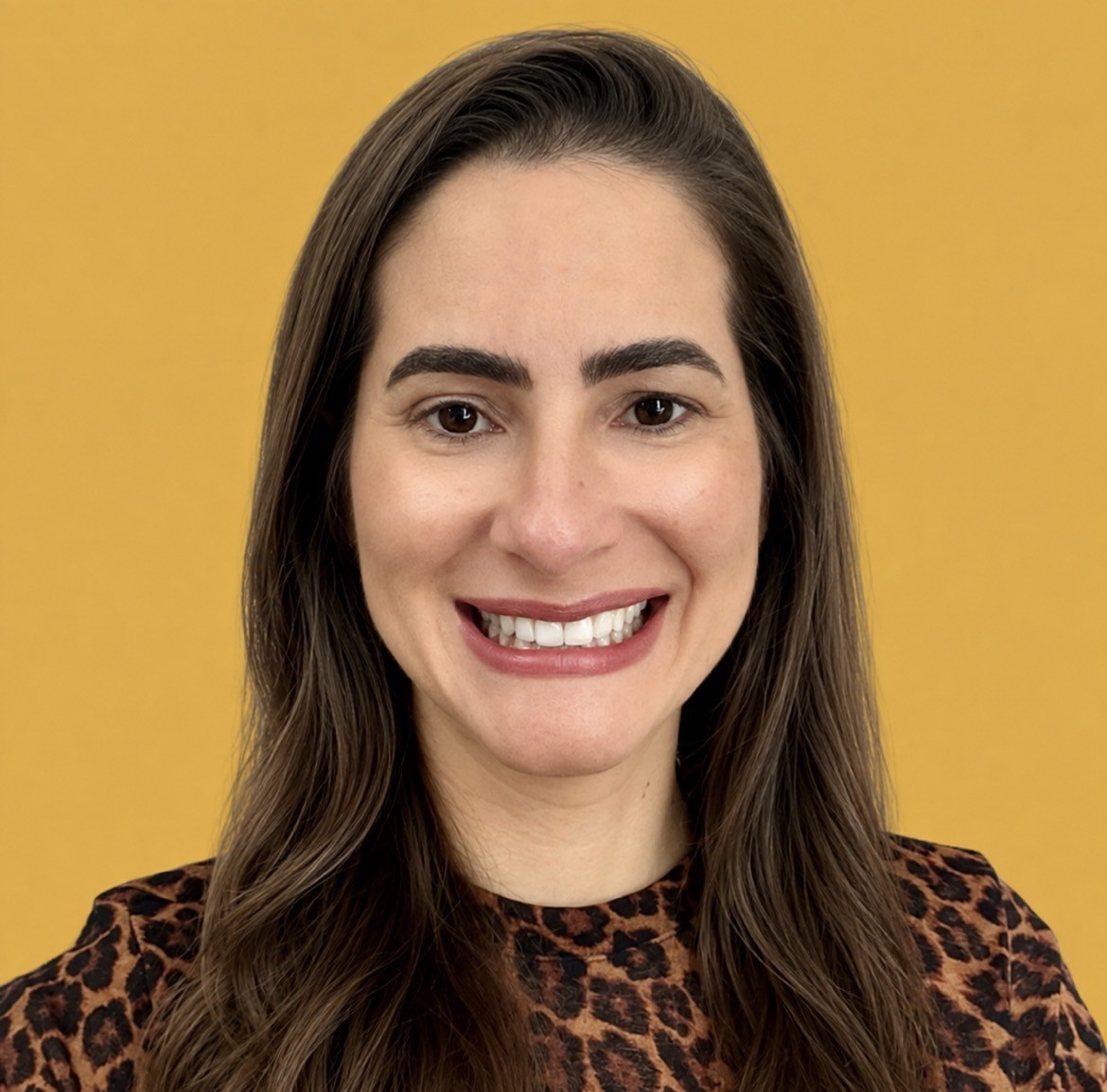 Headshot of Juliana Smith against a golden-yellow background, wearing a brown and black patterned top.