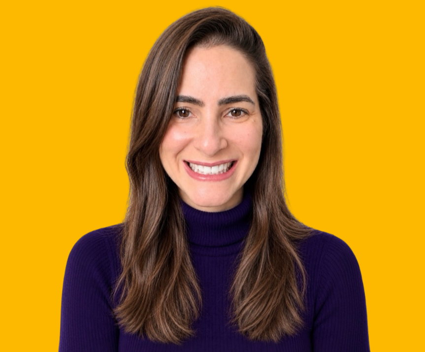 Photo of Juliana Smith against a solid yellow background. Juliana is centered in the frame, wearing a dark purple turtleneck sweater, with long brown hair and a direct-facing professional headshot composition.